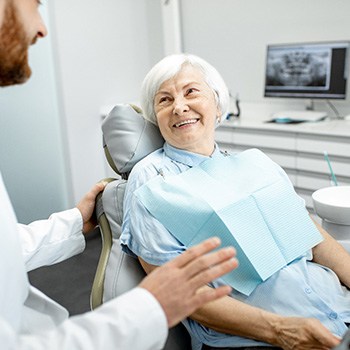 An older woman talking to her dentist about her new dental bridge