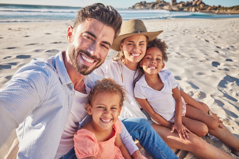 Family smiling on the beach after a dental checkup